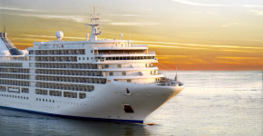Luxury cruise ship sailing from port on sunset